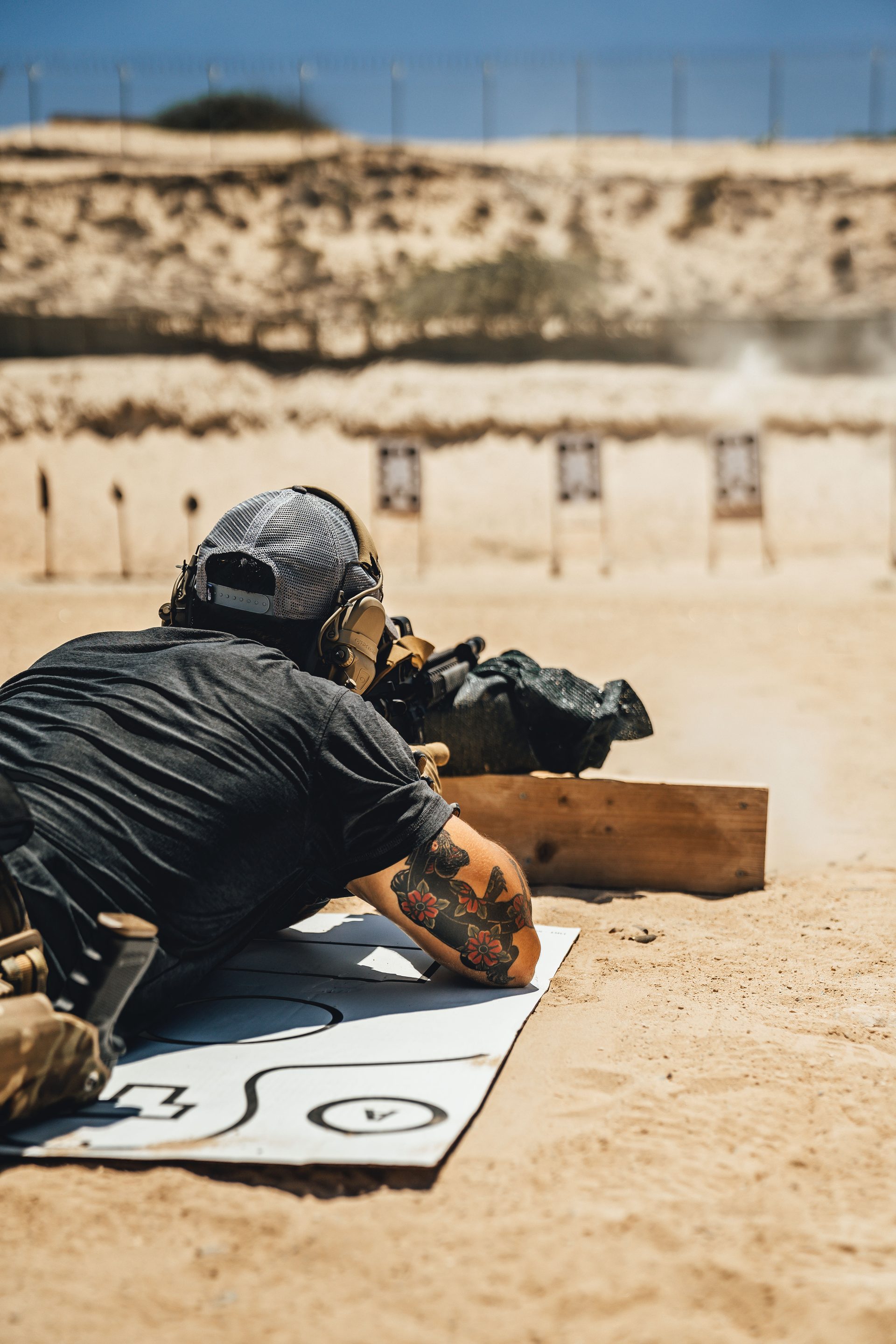 Operator in prone position firing rifle at shooting range